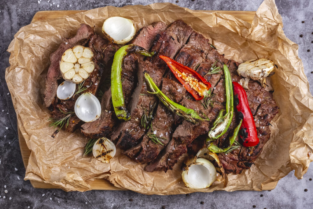 top-view-medium-cooked-steak-with-garlic-onion-red-chili-pepper-parchment-paper (1)