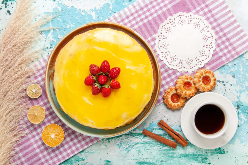 top-view-delicious-cake-with-yellow-syrup-fresh-red-strawberries-light-blue-background-biscuit-cake-bake-sweet-sugar-pie-tea-cookies